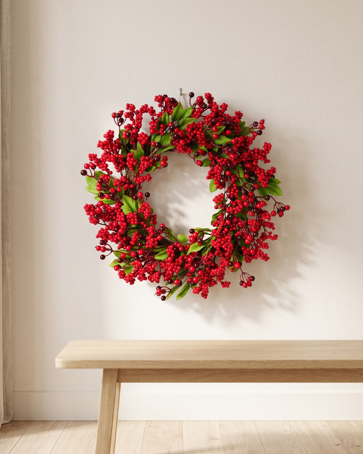 Berry and leaf Christmas wreath hanging on a plaster wall above a bench
