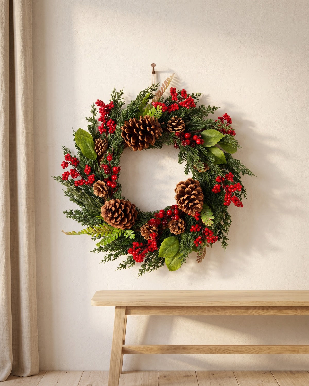 Cypress and pinecone Christmas wreath hanging on a plaster wall above a bench