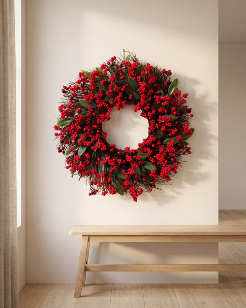Berry and twig Christmas wreath hanging on a plaster wall above a bench