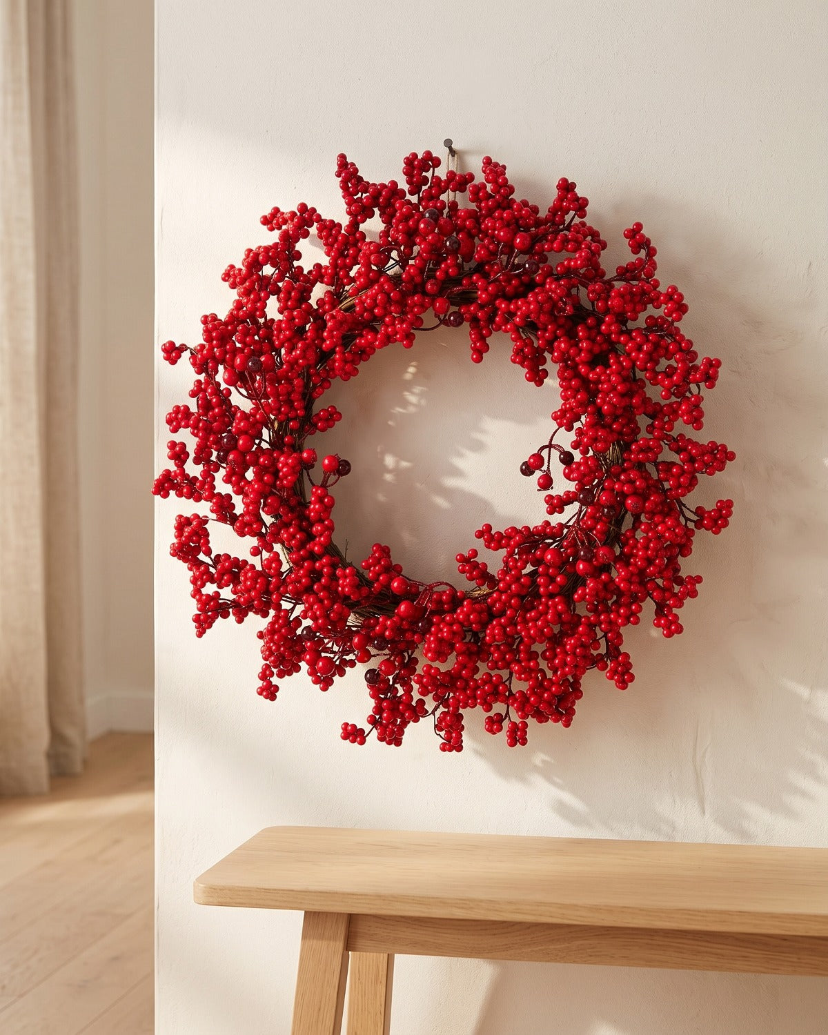 Red berry Christmas wreath hanging on a plaster wall above a bench